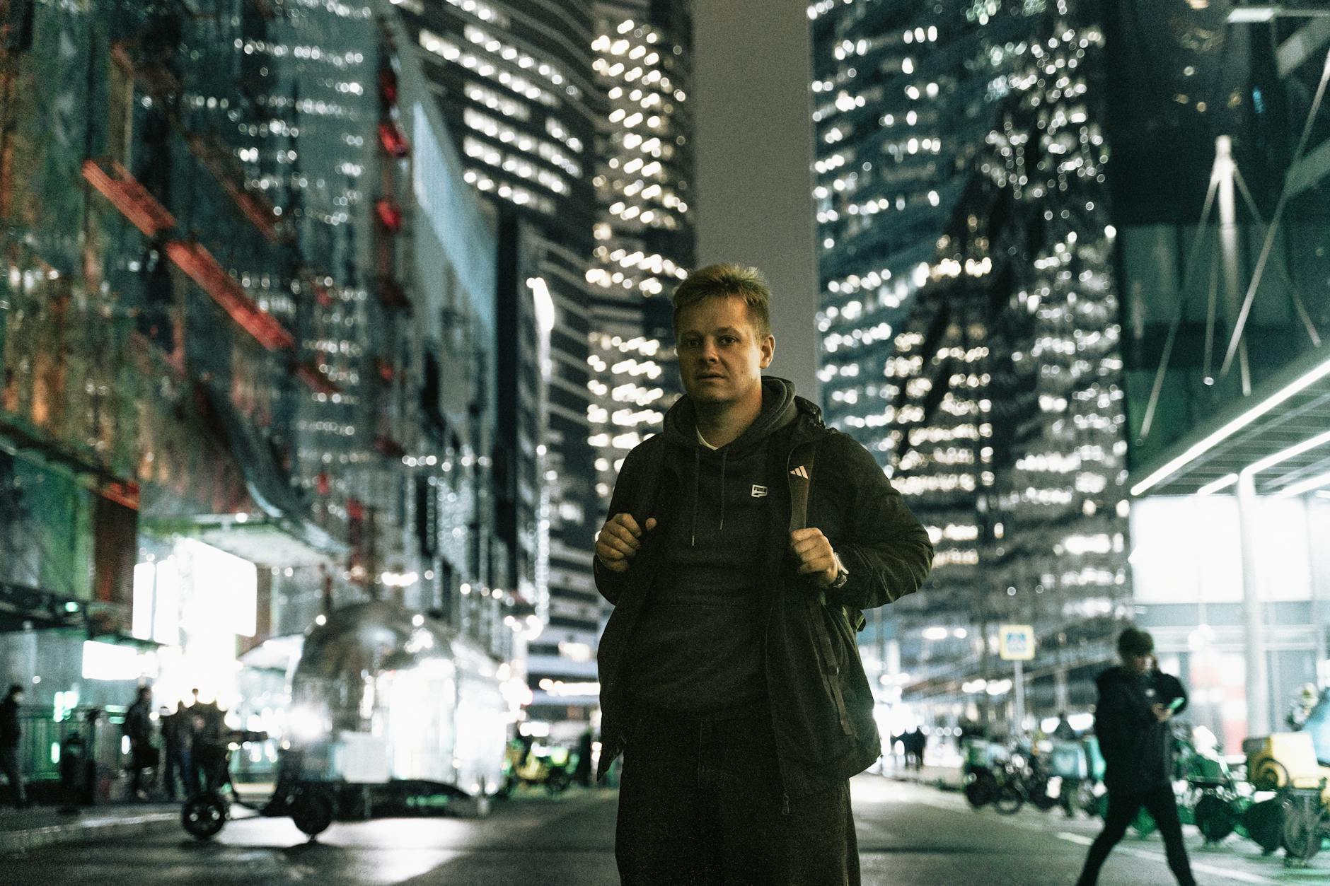 Młody mężczyzna na nocnej, jasno oświetlonej ulicy Moskwy Młody mężczyzna na nocnej, jasno oświetlonej ulicy Moskwy