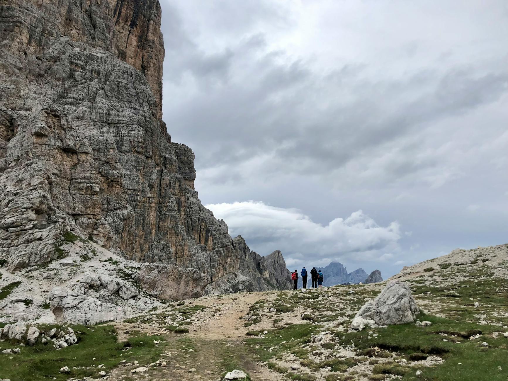 Turyści na górskim szlaku w Dolomitach przy pochmurnym niebie