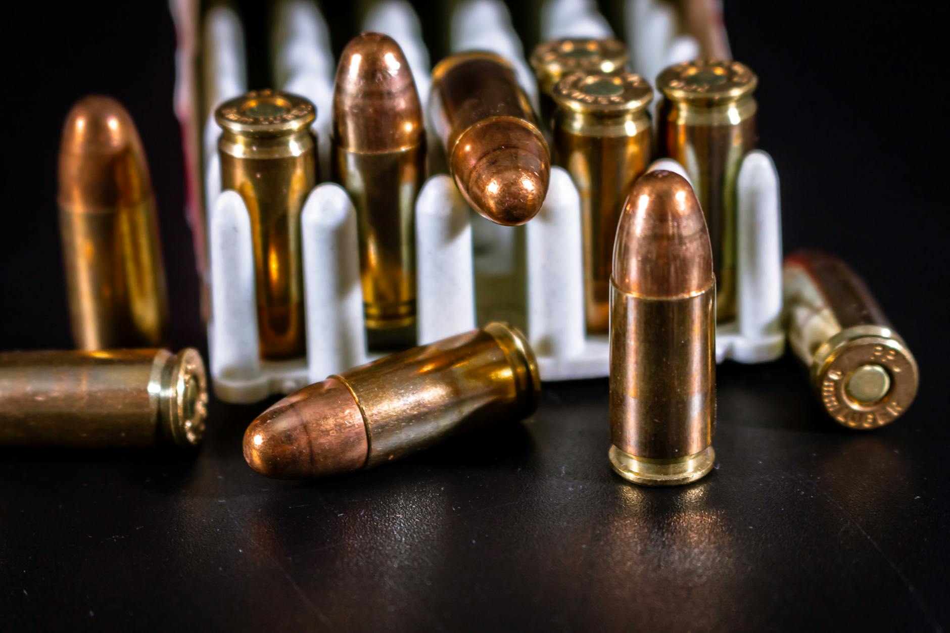 Zbliżenie na ułożone naboje 9×19 i .45 ACP na czarnym tle