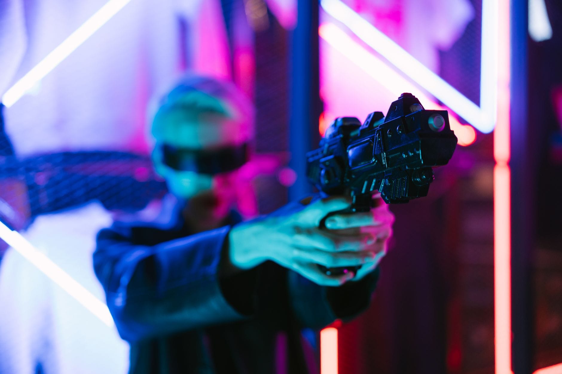 Kobieta w stylu cyberpunk trzyma futurystyczną broń na tle neonów
