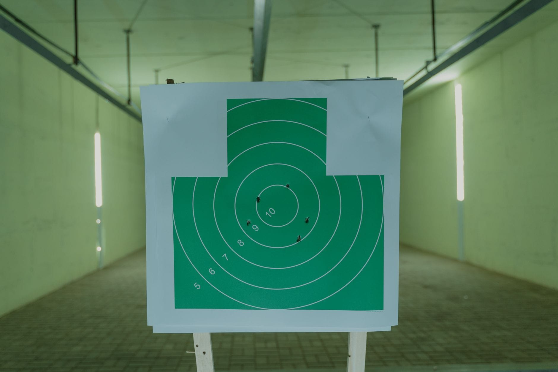 Zielona tarcza strzelecka z otworami po pociskach na strzelnicy indoor